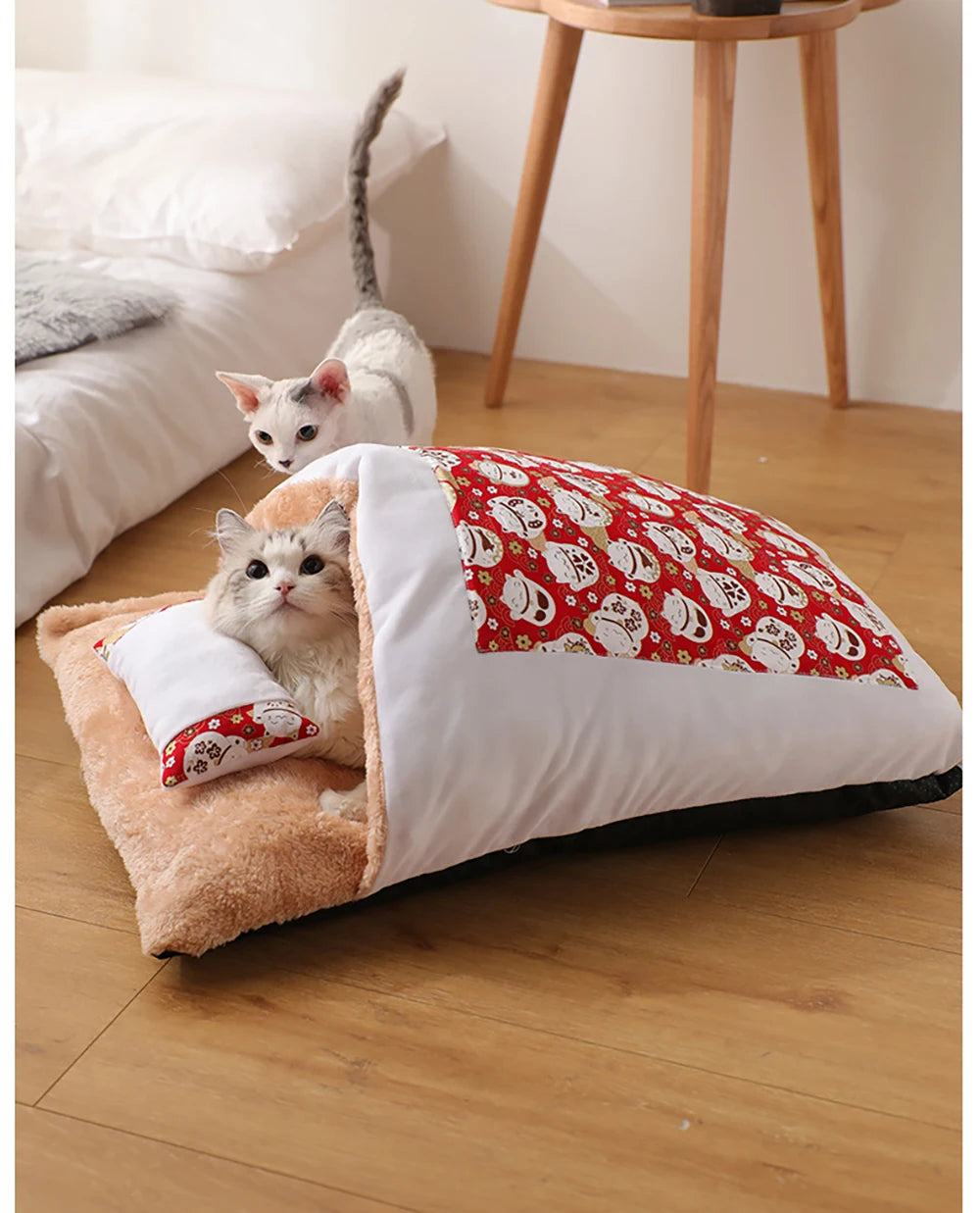 Two cats snuggled in red and navy pet sleeping bag beds